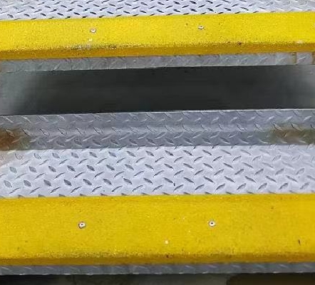 OCEANFRP's Bright yellow FRP anti-slip stair treads secured onto industrial metal staircase for improved safety and grip.